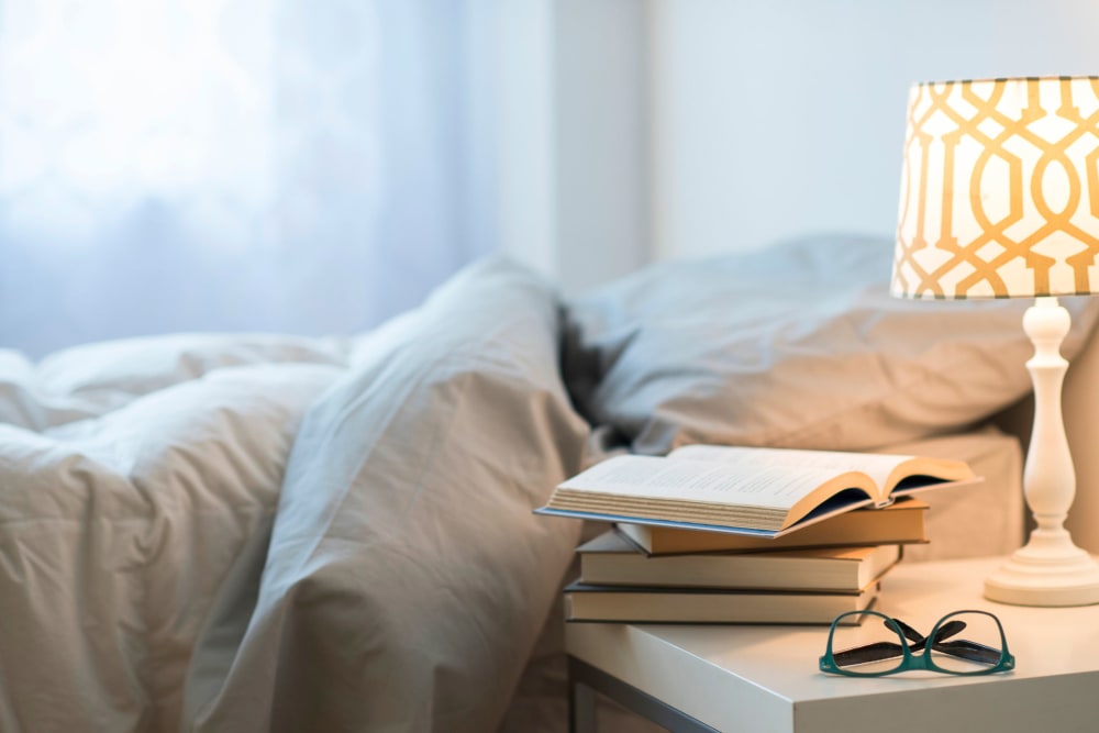 A bed and night stand with a book on it at Harbor Cove Memory Care in Hilton Head Island, South Carolina