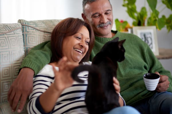 A happy couple and their cat at Flats of Forestville Apartment Homes in Forestville, Maryland