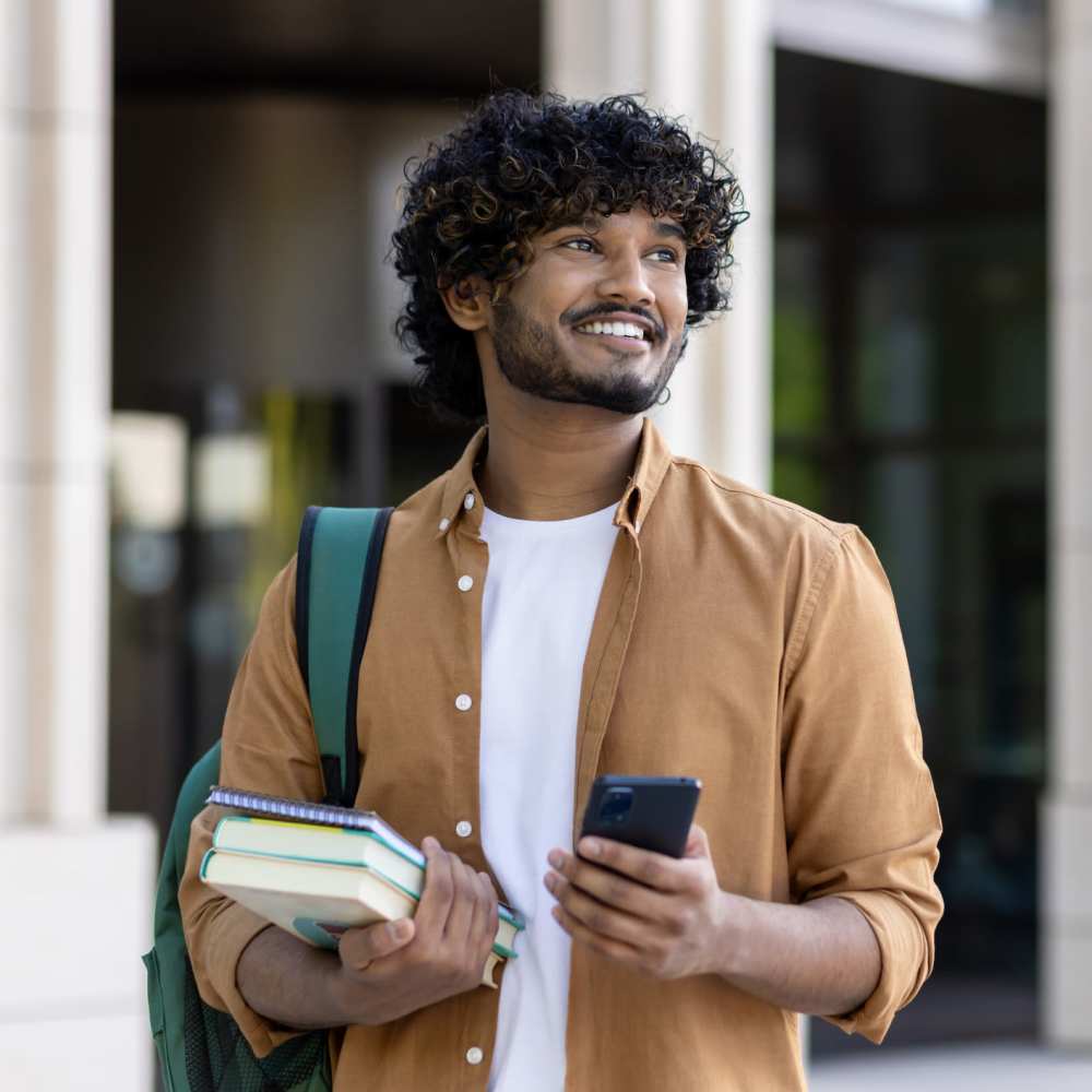 Young man with curly hair holding books and phone The Simone in Silver Spring, Maryland