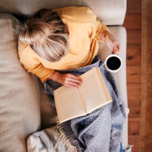 Resident reading a book with a cup of tea at Woodland Park in Arlington, Texas