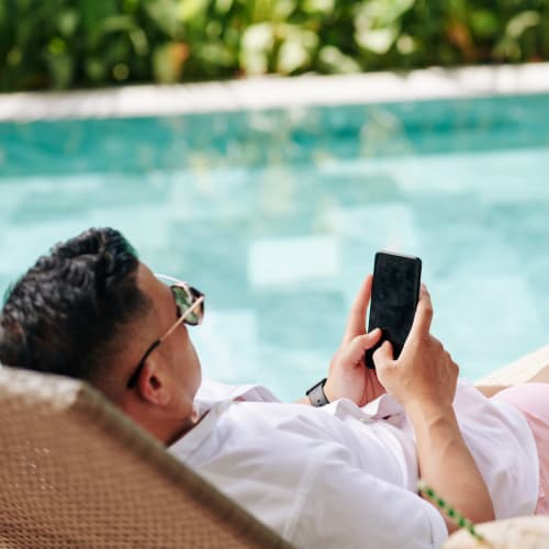 Resident sitting in a sunny poolside lounge chair at Solaire 1150 Ripley in Silver Spring, Maryland