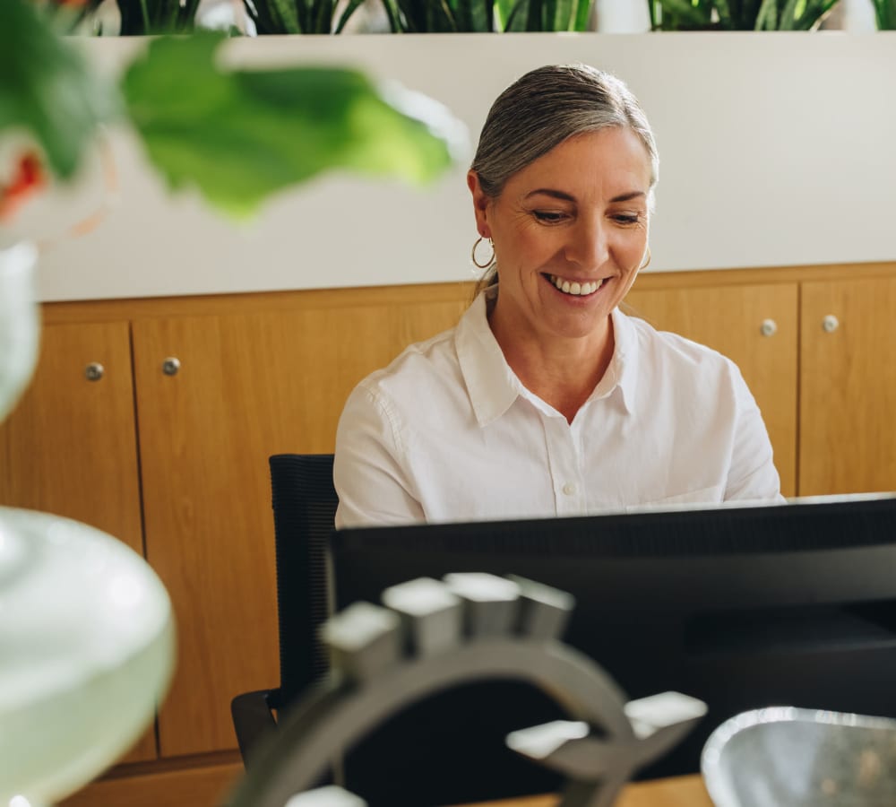 Smiling woman working on the computer at her desk at Graham Residential in Miami Lakes, Florida