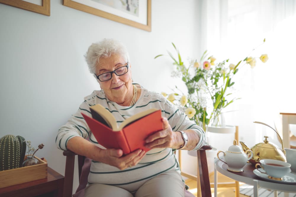 Resident sitting on chair reading at Vista Prairie at North Pointe in North Mankato, Minnesota