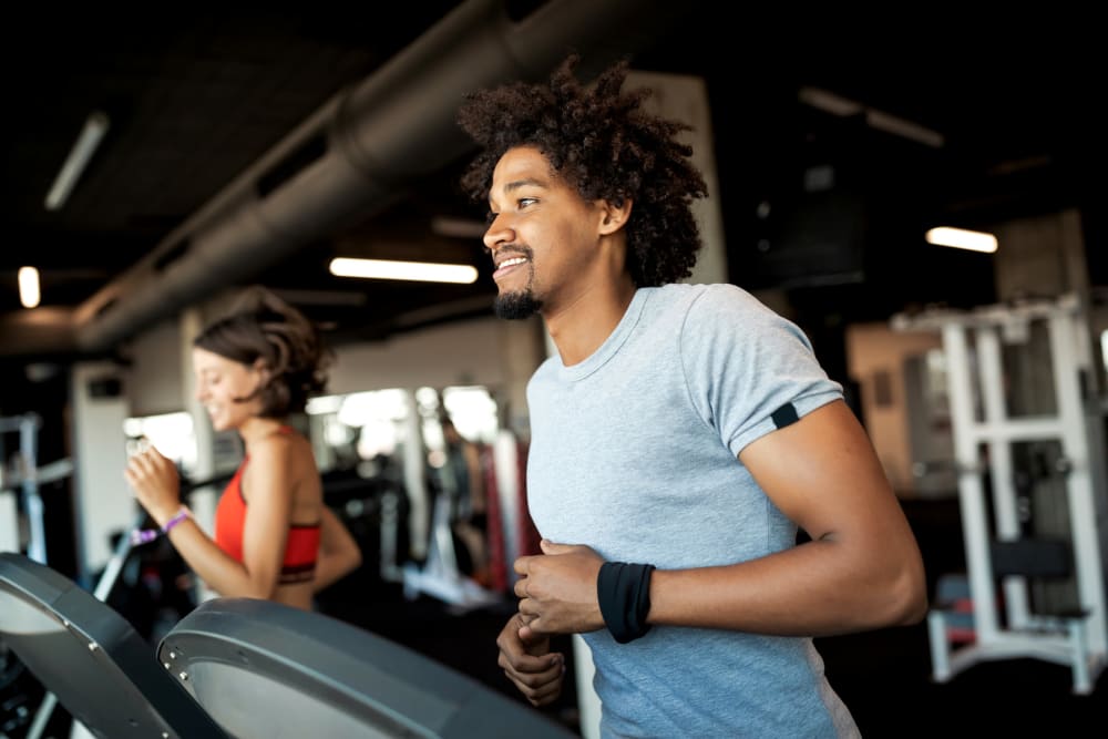 Resident running on a treadmill in the fitness center at Creekside Village in Alexandria, Virginia