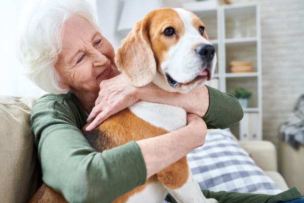Happy resident hugging dog at Maplewood at Cuyahoga Falls in Cuyahoga Falls, Ohio