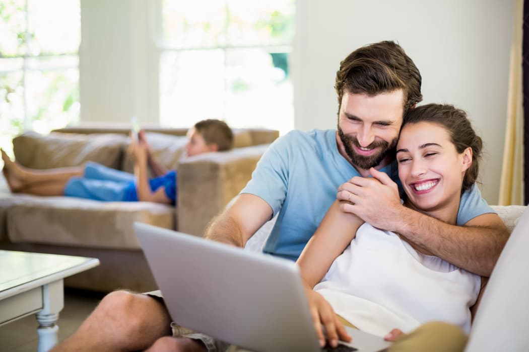 Happy couple surfing the web while child plays on phone in background at The Preserve at Hardin Valley in Knoxville, Tennessee