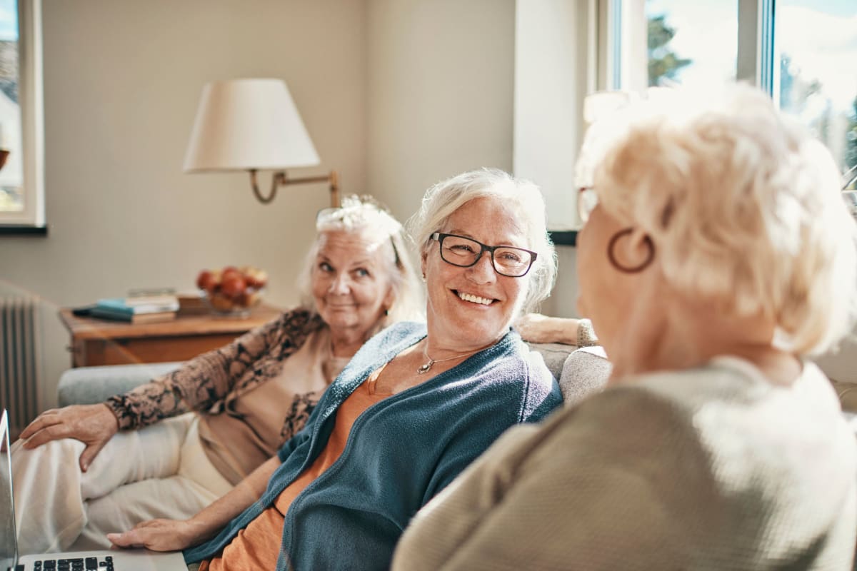 Three smiling friends sitting on a couch at Saunders House in Wahoo, Nebraska