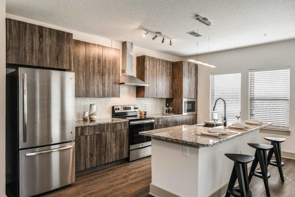 Apartment kitchen with stainless steel fridge and wooden cabinets at SoBA Apartments in Jacksonville, Florida