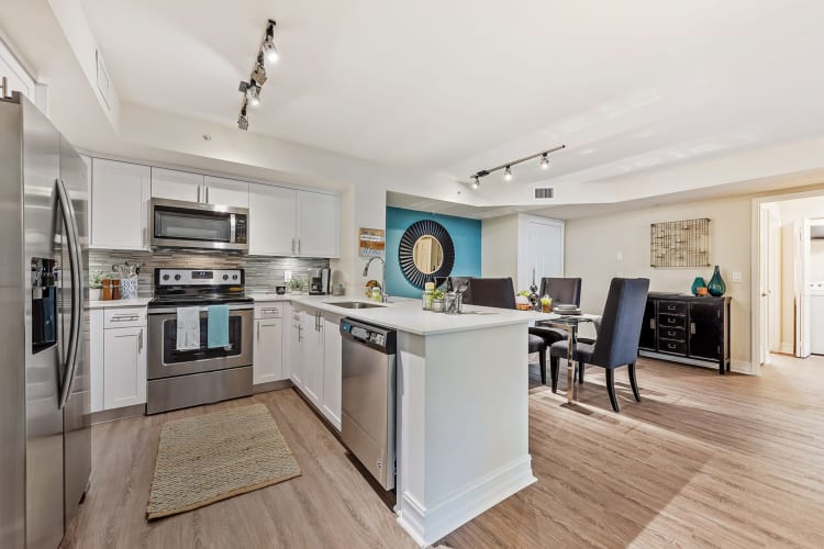 Model dining room and kitchen with stainless-steel appliances and granite countertops at Crescent House Apartments in Miami Lakes, Florida