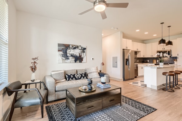 A comfortable, furnished apartment living room and bar seating at the kitchen island at Cypress McKinney Falls in Austin, Texas