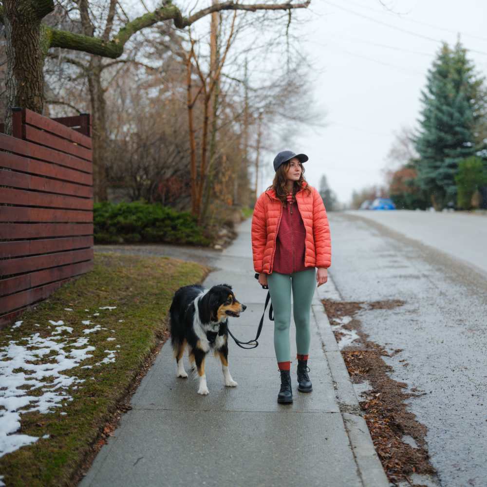 Luxury woman in red jacket walking dog on sidewalk at Commonwealth Landing Lofts in Fall River, Massachusetts