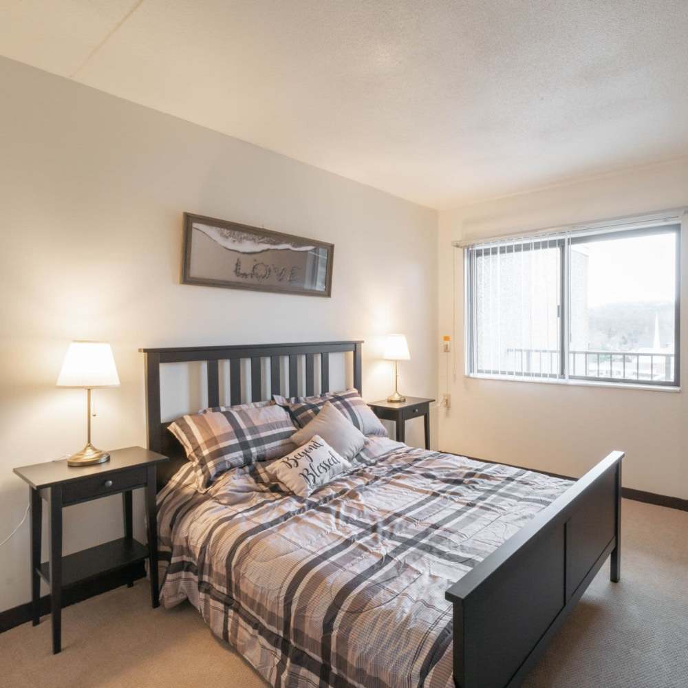 Modern-style bed and nightstand at Brookpark Place Apartments in Wheeling, West Virginia