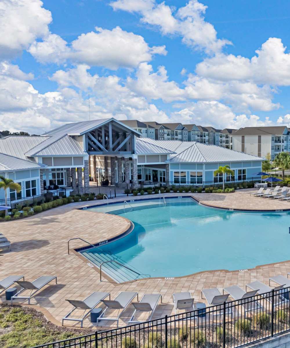 Outdoor pool with clubhouse and lounge area at The Carlton At Lake Dexter in Winter Haven, Florida