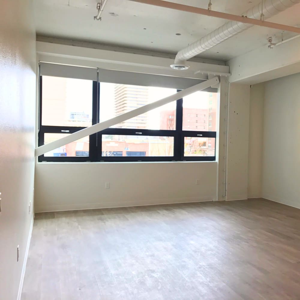 Bright living room with large windows, wood-style flooring, and open layout connecting to adjacent bedroom at 3rd Street Flats in Reno, Nevada