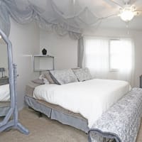 Cozy resident bedroom with large bed and mirror at Spring Creek Townhomes in Springfield, Illinois