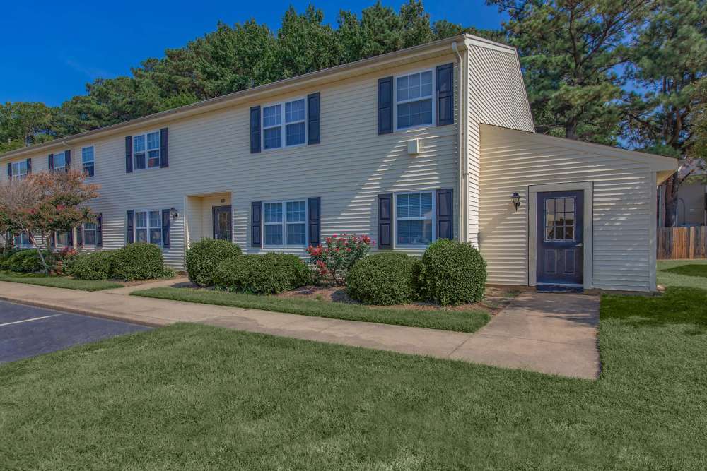 A wide exterior view of the apartment building with walk-ways and lawn grass at Village at Town Park in Hampton, Virginia