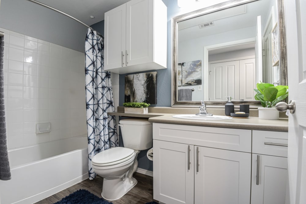 Bathroom with a large vanity mirror and oval tub at Ranch ThreeOFive in Arlington, Texas