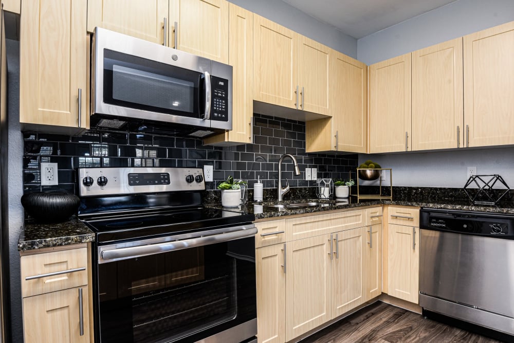 Stainless steel appliances and wood floors in kitchen at Ranch ThreeOFive in Arlington, Texas