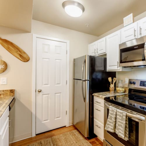 Apartment kitchen with wood-style flooring and stainless-steel appliances at UTE Creek Apartments in Longmont, Colorado