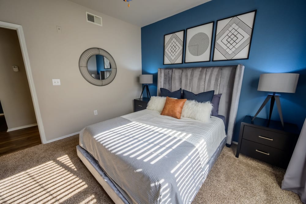 Plush carpeting and an accent wall in the primary bedroom of a model apartment at 23Hundred @ Ridgeview in Plano, Texas