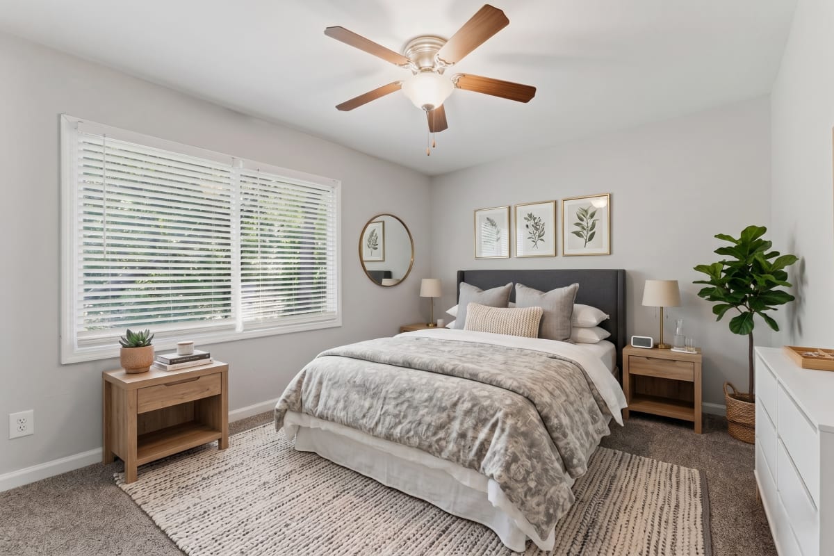 Cozy bed with ceiling fan and carpet flooring at Broadway at East Atlanta in Atlanta, Georgia