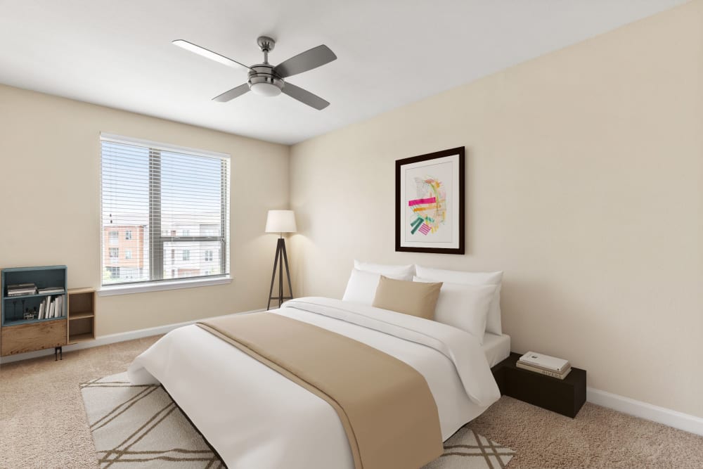 Model bedroom with plush carpeting, ceiling fan, and ensuite bathroom at The Point at Town Center in Jacksonville, Florida