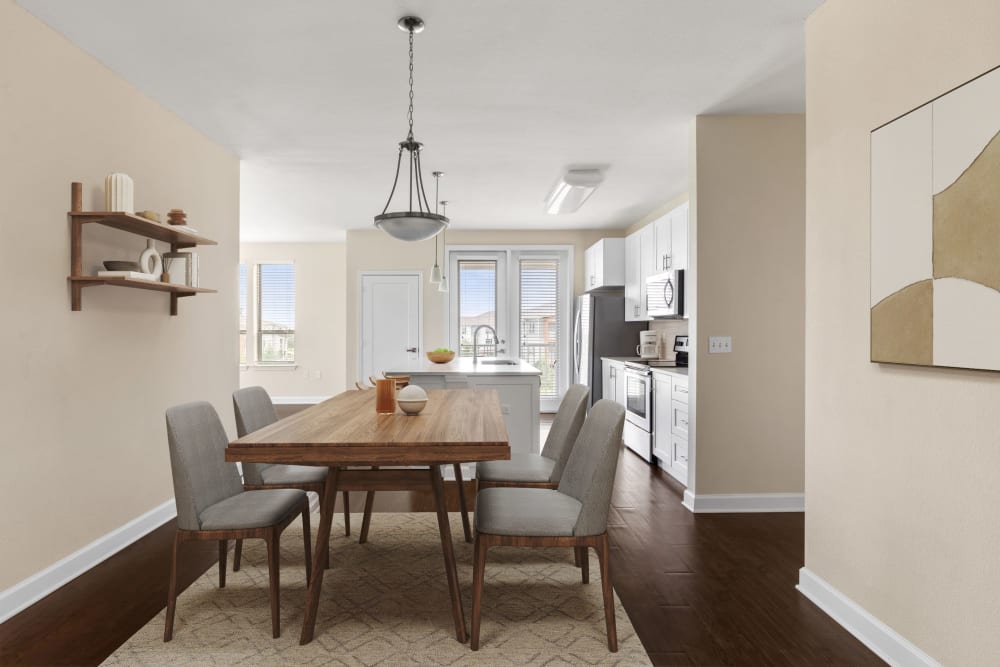 Dining area and kitchen with wood-style flooring and designer lighting at The Point at Town Center in Jacksonville, Florida