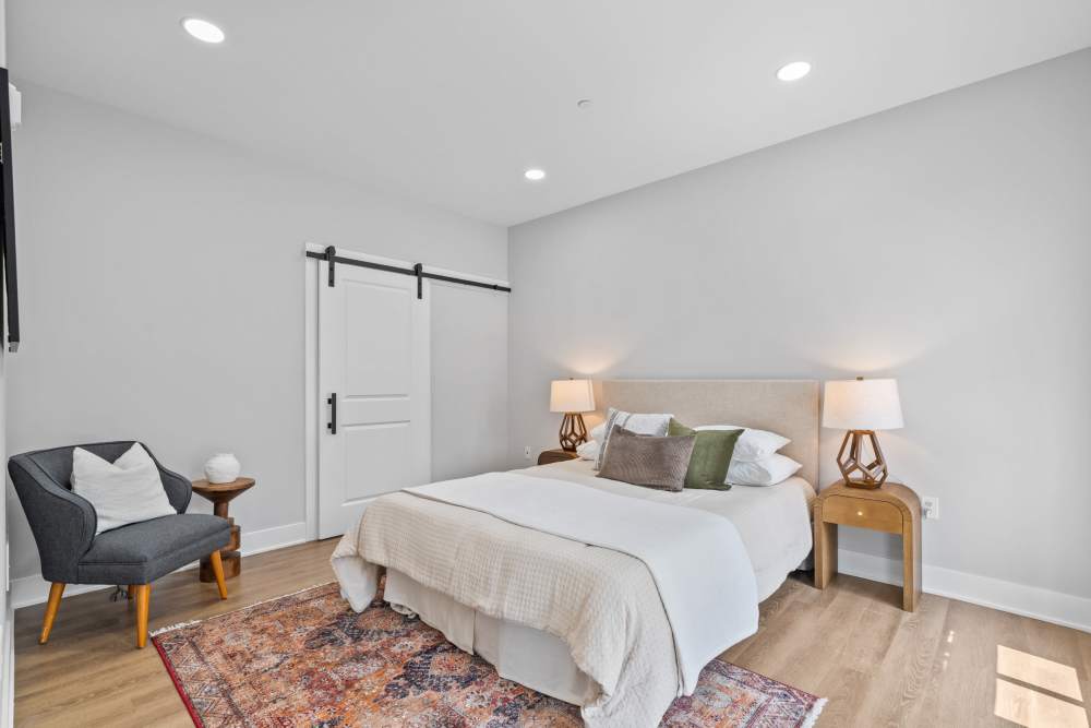 A cozy bedroom featuring a neatly made bed, a comfortable chair, and a soft rug on the floor at Landmark at Dublin in Dublin, Pennsylvania