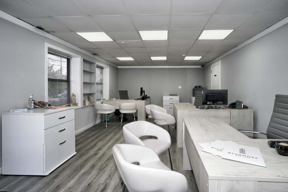 Bright office space with modern furniture, wood-style flooring, and natural light from large windows at Dutch Village Apartments in Baltimore, Maryland