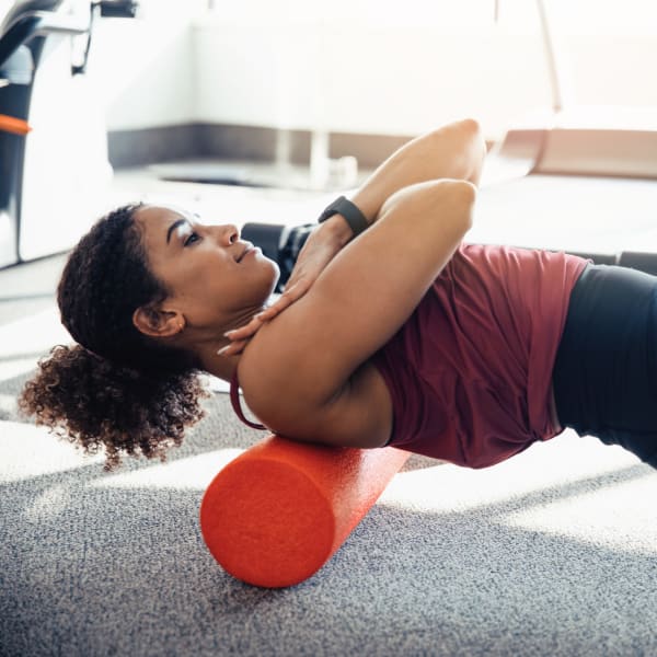 Resident stretching with a foam roller at Olympus Chandler at the Park in Chandler, Arizona