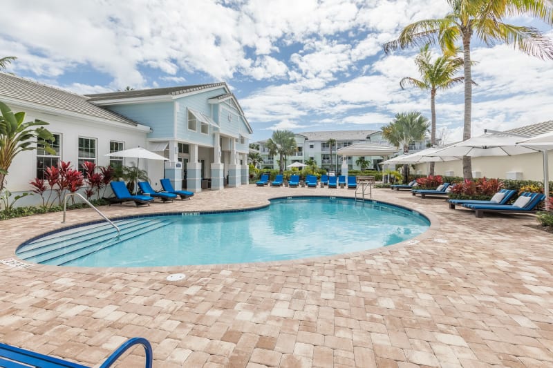 Resort-style swimming pool flanked by chaise lounge chairs and lush vegetation at High Ridge Landing in Boynton Beach, Florida