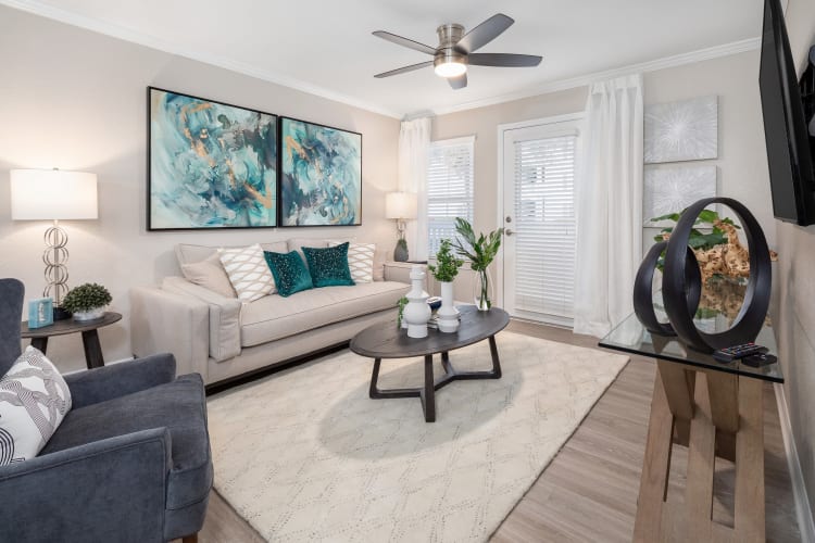 Well-furnished model home's living area with a ceiling fan at Amira at Westly in Tampa, Florida