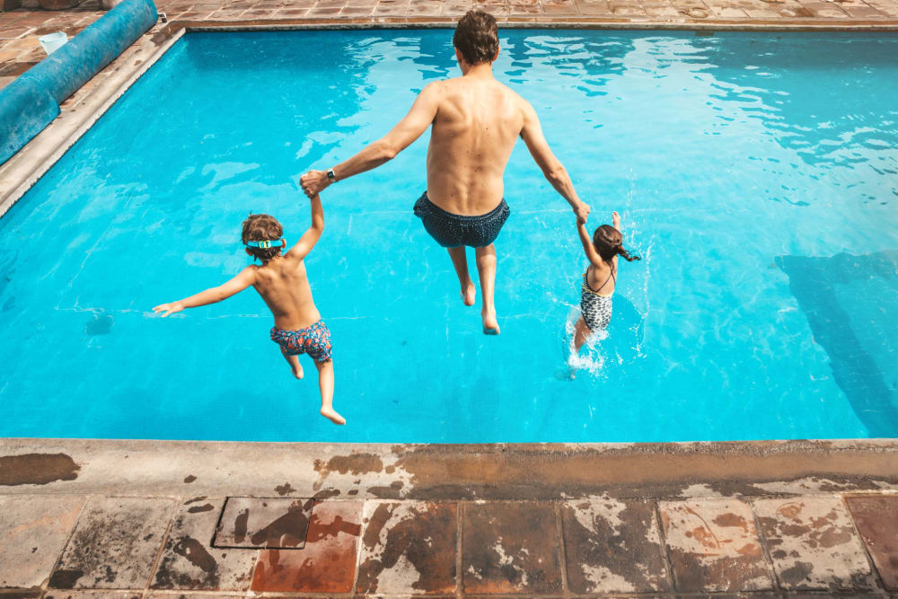 A resident and two kids jumping into the pool at Enclave at Woodcrest Station in Cherry Hill, New Jersey