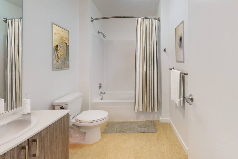 Bathroom with wooden vanity, toilet, sink and shower curtain atThe Union in Portland, Oregon
