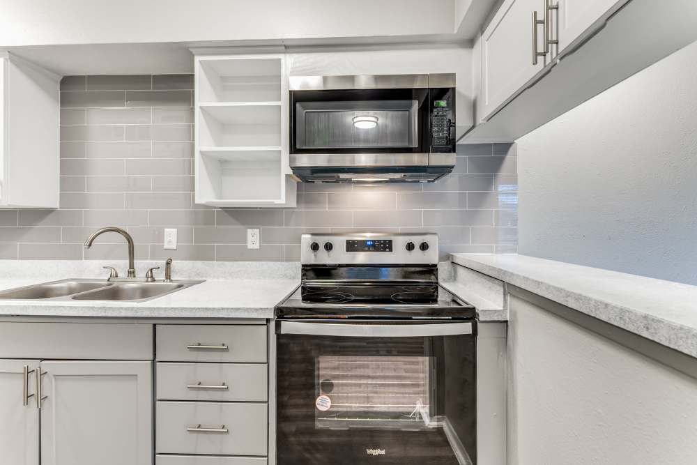 Modern kitchen with stainless-steel appliances and white wood cabinet at Tribecca Pointe Apartments in Hurst, Texas