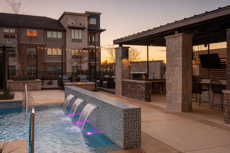 Outdoor pool area with seating and places to entertain poolside at Domain at Founders Parc in Euless, Texas
