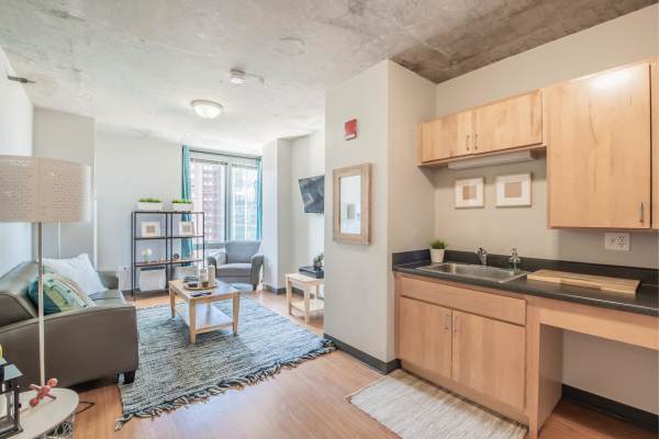 Living area with kitchen and seating area at The Flats at East West University in Chicago, Illinois
