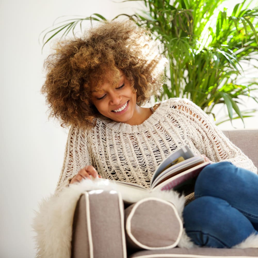 Resident reading a book on her couch at The Metro at Clearview in Metairie, Louisiana