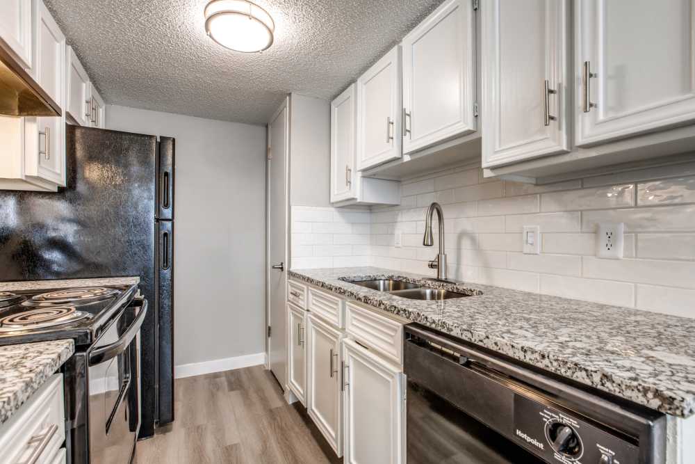 Kitchen with granite counter top and white cabinetry at Villa De Oro in San Antonio, Texas