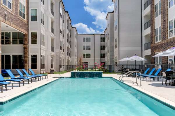 Swimming pool with lounge chairs and umbrellas at Dakota at Shepherd in Houston, Texas