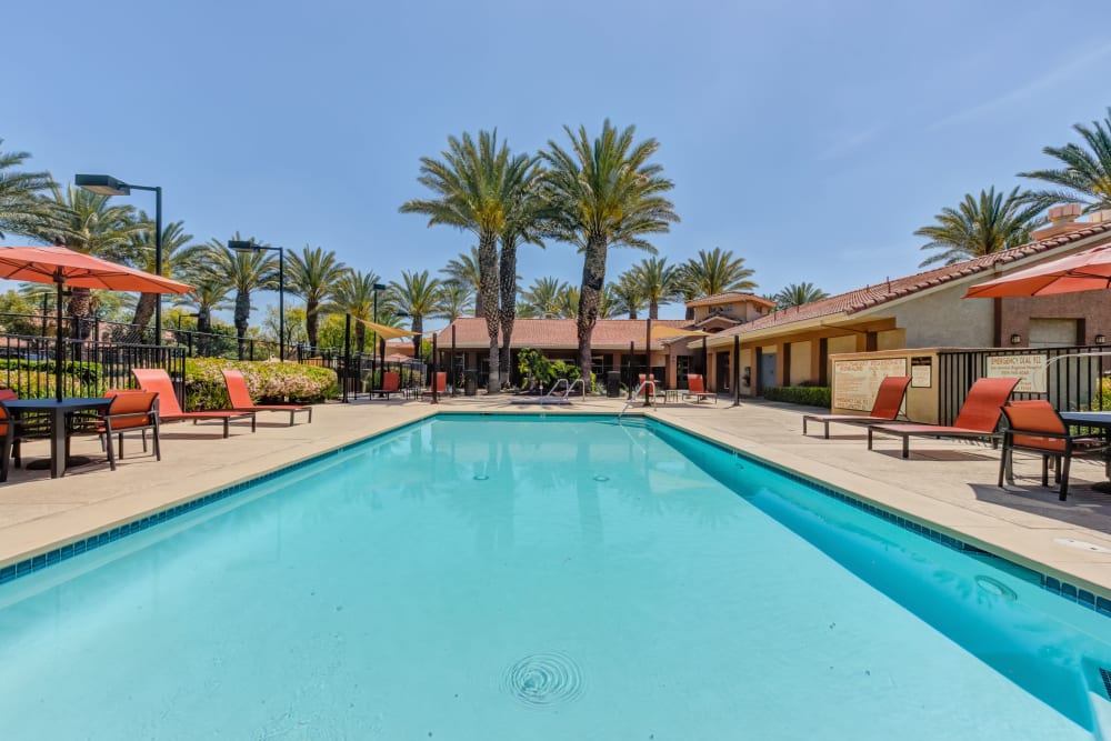 Large swimming pool with a sundeck and lounge chairs at Tuscany Village Apartments in Ontario, California