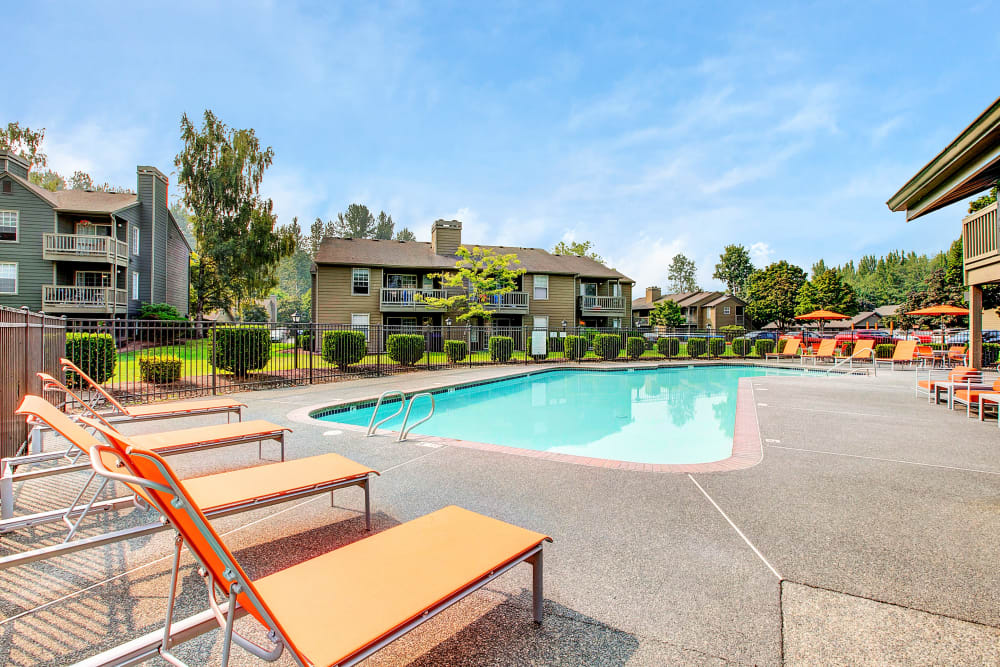 Beautiful resort-style swimming pool with lounge chairs at Waters Edge Apartments in Kent, Washington