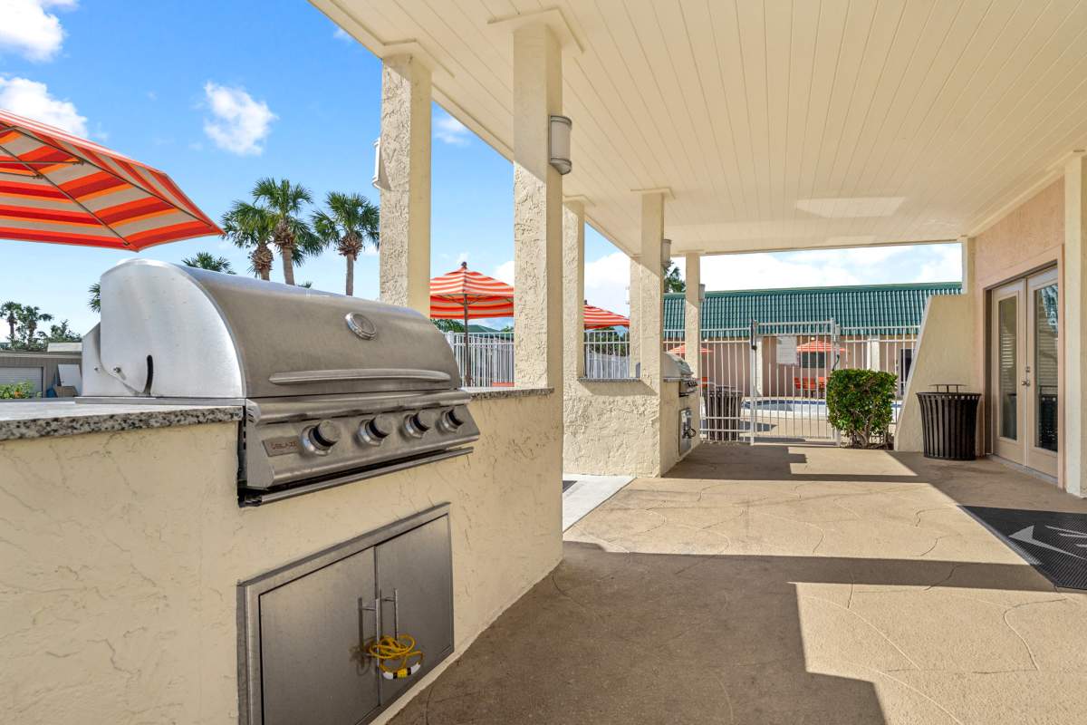 Outdoor picnic seating and grills with swing-set in background at Buena Vista in Seminole, Florida