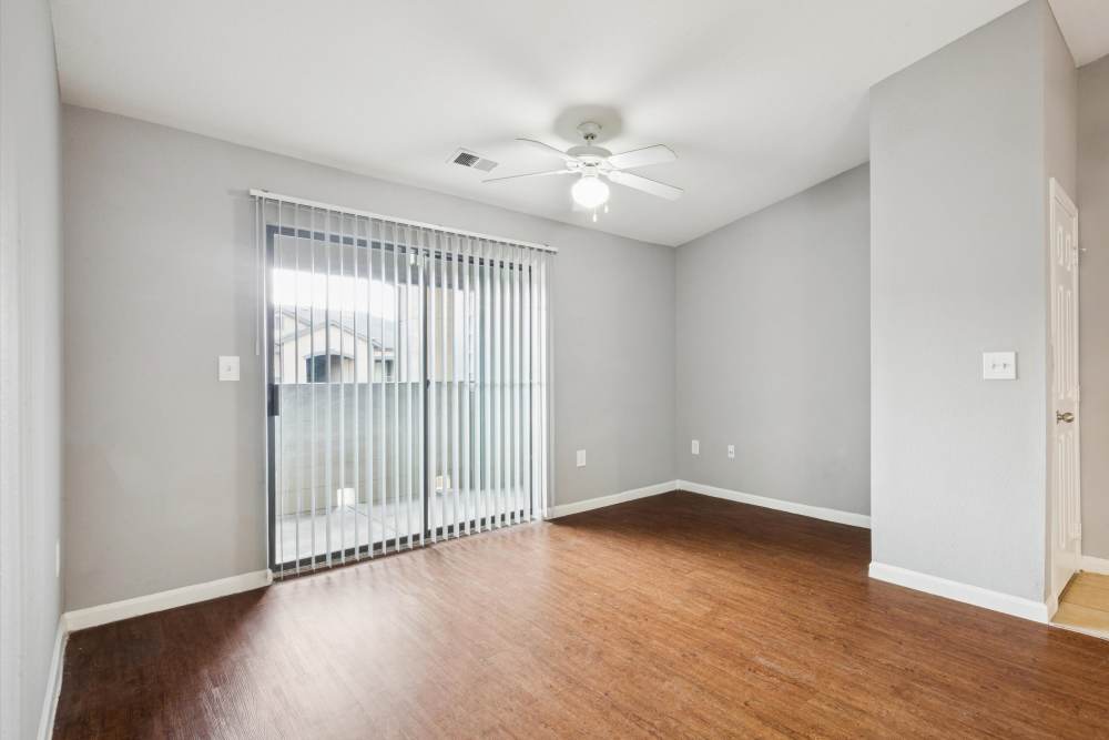 Living area of apartment with ceiling fan and wood style flooring at Lansbourough in Houston, Texas