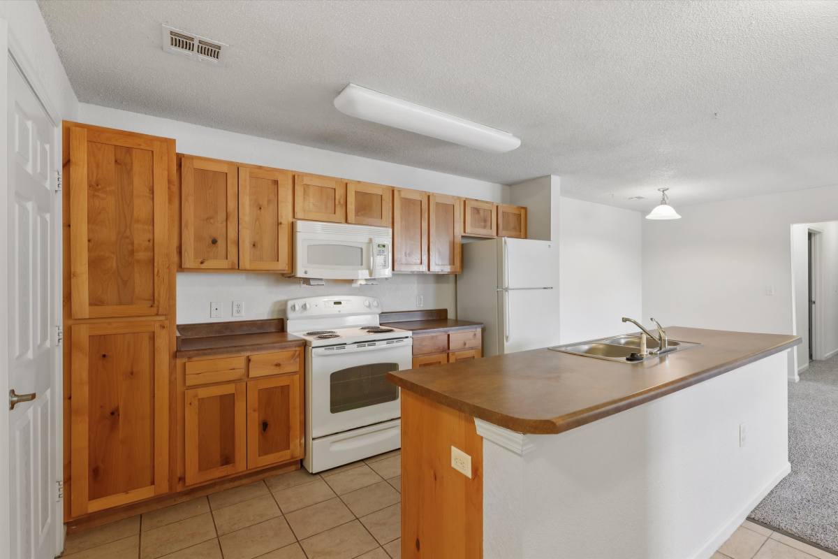 Modern kitchen with wooden cabinets at Covington Woods Apartments in Lansing, Kansas