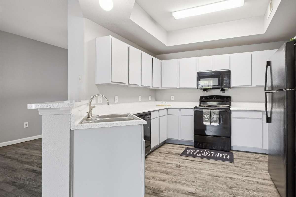 Apartment kitchen with energy-efficient appliances and white cabinets at Lansbourough in Houston, Texas