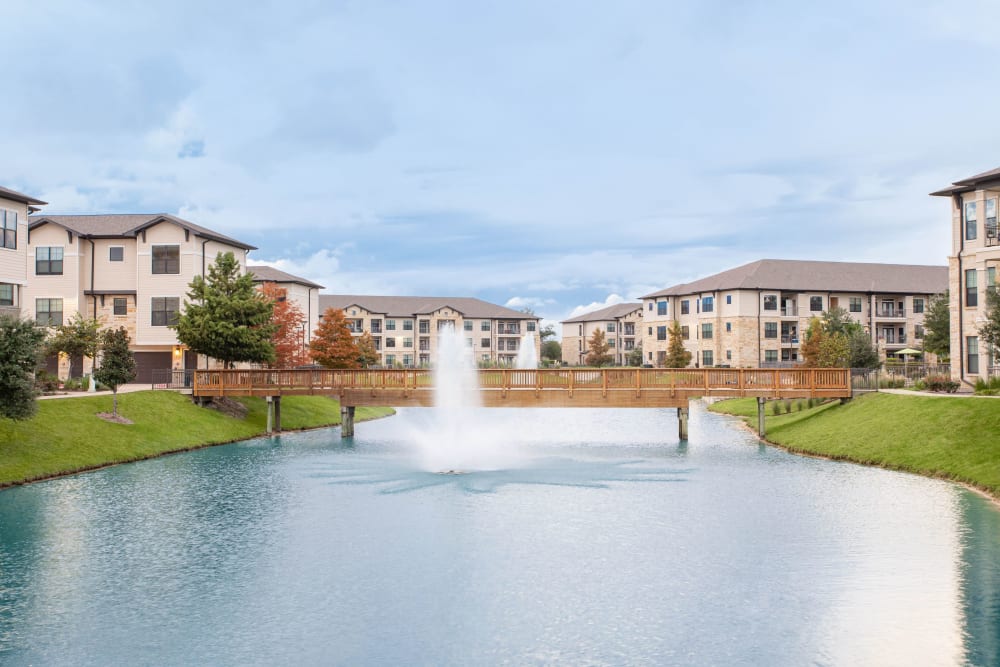 Scenic walkway along lake and building units at Olympus Falcon Landing in Katy, Texas