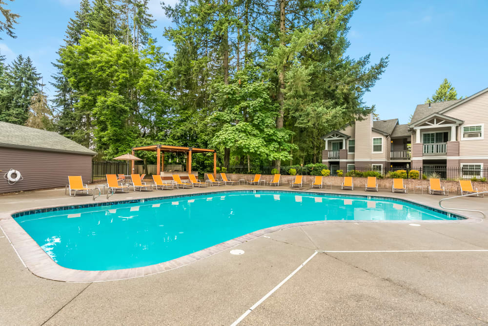 Beautiful blue pool surrounded by orange lounge chairs at Autumn Chase Apartments in Vancouver, Washington