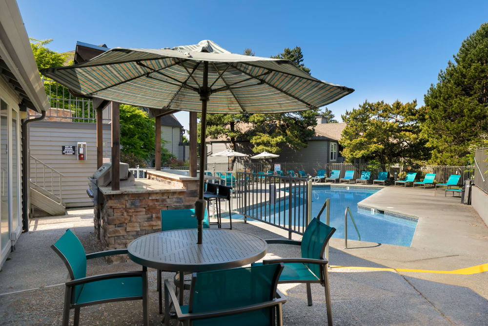 Beautiful resort-style swimming pool with lounge chairs and a barbecue area at Meadows at Cascade Park Apartments in Vancouver, Washington
