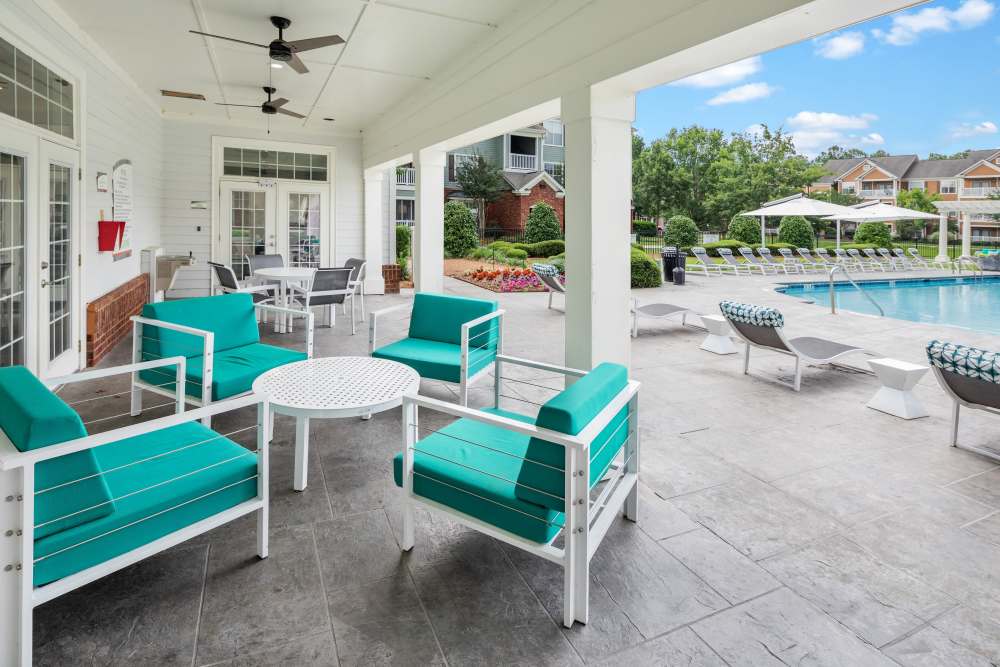 Charming lounge area with vibrant turquoise seating overlooking a sparkling water pool at Bryant at Summerville in Summerville, South Carolina.